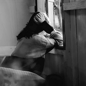 Frau schaut gedankenverloren aus dem Fenster.